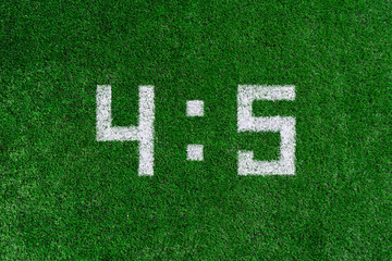 Football score 4:5.White numbers four and five are drawn on the green grass,creative scoreboard