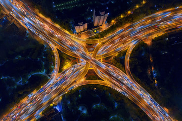 Aerial view of highway junctions shape letter x cross at night. Bridges, roads, or streets in...