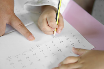 hand of child or student holding pencil and study with learning writing number and mathematics on...