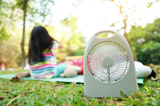 Mini fan 5V USB or 12VDC item for cool picnic or family camping relax on summer season and hot weather on green grass meadow in national park jungle for vacation on holiday travel with warm sunlight