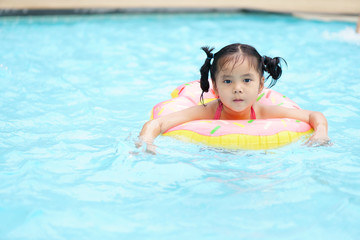Asian child cute or kid girl swimming wear life ring because can not swim and happy fun on swimming pool or water park for refreshing and relax with exercise at summer holiday travel in hotel resort