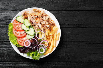 Doner kebab or gyros on a plate with french fries, pita bread and salad. - obrazy, fototapety, plakaty