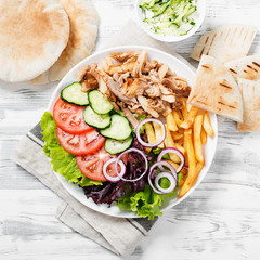 Doner kebab or gyros on a plate with french fries, pita bread and salad.
