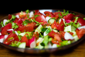 Close-up, delicious fresh vegetable salad cucumber tomatoes radishes cheese greens, vegetarian cuisine, healthy food, diet