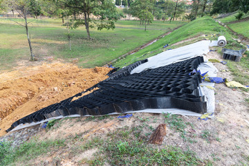 Slope erosion control grids, sheets and earth on steep slope