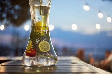 Modern Hookah for tobacco smoking made of metal, glass and plastic on wooden table.The background-summer sunny garden. Selective focus.