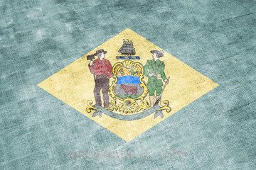The national flag of the US state Delaware in against a gray textile rag on the day of independence in different colors of blue red and yellow. Political and religious disputes, customs and delivery.