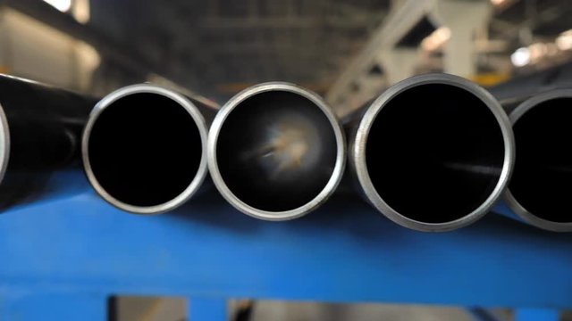 Rows of Metal Pipes with reflections and Sun Flares inside. Steel pipes at metal factory.