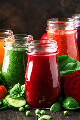 Colorful vegetable juices and smoothies from tomato, carrot, pepper, cabbage, spinach, beetroot in bottles on kitchen table, vegan food and drink, selective focus