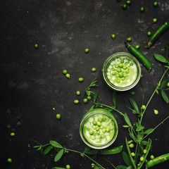 Cream green peas soup in glass jar on gray kitchen table, copy space, selective focus