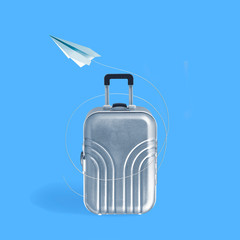 Silver travel suitcase and paper plane