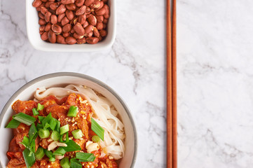 shan noodles with peanuts and chopsticks at white marble tabletop. burmese cuisine traditional dish. myanmar food. rice noodles with pork in tomatoes. copy space. top view