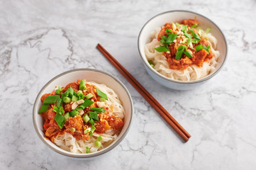 shan noodles with chopsticks at white marble tabletop. burmese cuisine traditional dish. myanmar food. rice noodles with pork in tomatos. asian dish