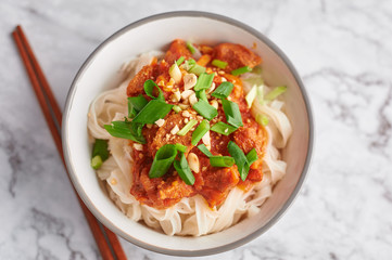 shan noodles with chopsticks at white marble tabletop for two persons. burmese cuisine traditional dish. myanmar food. rice noodles with pork in tomatos. asian dish. 