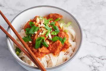 shan noodles with chopsticks at white marble tabletop. burmese cuisine traditional dish. myanmar food. rice noodles with pork in tomatos. asian dish