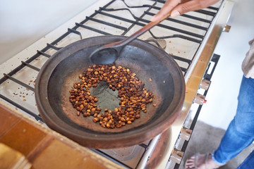 Black woman roasting coffee beans traditionallly in a pan / The only coffee plantation in Europe on Gran Canary Island
