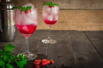 Fresh Ice Mulberry Soda drink on the wood table there are Mulberry, Leaves, cocktail shaker and same object placed around.