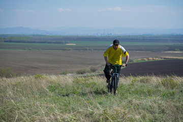 Fototapeta na wymiar A man rides a bicycle out of town on rough terrain.