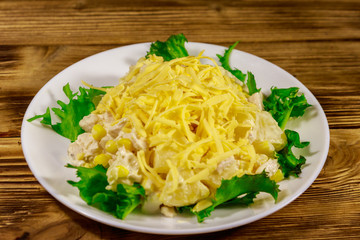 Festive salad with chicken breast, sweet corn, canned pineapple, cheese and mayonnaise on wooden table