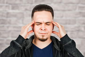 man taking antibiotic, antidepressant, pill medication to relieve pain at home. Young guy sick, ill suffering from headache, stress or flu, emergency treatment concept on brick wall background