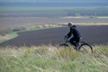 A woman on a bike rides over rough terrain.
