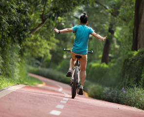 Woman riding a bike on sunny park trail with no-hands