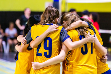 Female volleyball players huddling together before starting the game