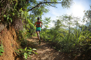 Naklejka na ściany i meble Young fitness woman trail runner running in summer forest