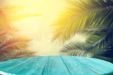 Summer background of wooden table and beach background with palms 