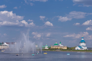 Naklejka na ściany i meble boats with vacationers on the Bay in Cheboksary on the background of the fountain and the historical part of the city,shot on a clear and warm spring day