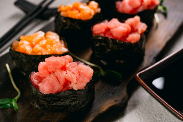 Salmon and tuna gunkan maki sushi roll set on wooden platter served with soy sauce and chopsticks. Japanese traditional culinary style, restaurant menu, food blog