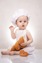 little boy in the cook costume with bread. laughing happily