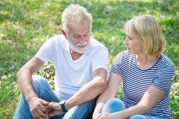 Happy senior couple relaxing at park together in morning time. old people sitting on grass in the autumn park . Elderly resting .mature relationships. family