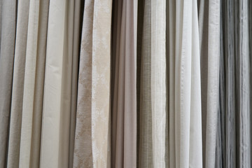 Beautiful curtains of different colors hang on the stand for sale. Curtains hang on the stand in the store