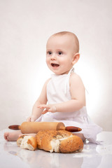 little boy in the cook costume at the kitchen with bread