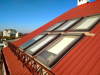 Red tiled house roof with attic windows. Roofing construction, window installation, modern...