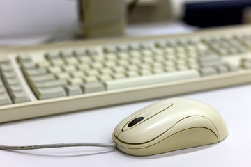 Close-up of white computer mouse on blurred PC keyboard background. Modern technology, information and communication concept.