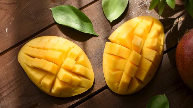 Top view of mango halved and cut into cubes on wooden table