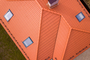 Aerial top view of house metal shingle roof, brick chimneys and small plastic attic windows. Roofing, repair and renovation work. - obrazy, fototapety, plakaty
