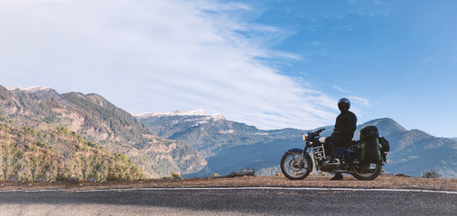 A young unidentifiable man sitting on his motorbike with view of Himalayan mountains. © Abhishek