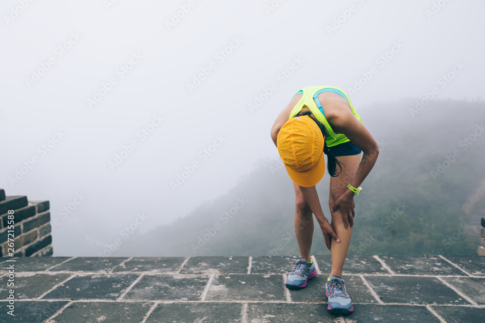 Sticker woman trail  runner hold her sports injured legs at the top of mountain