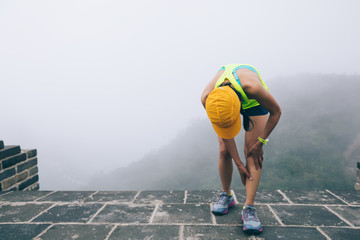 woman trail  runner hold her sports injured legs at the top of mountain