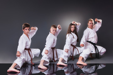 Group of young karate players doing kata on the gray background - Powered by Adobe