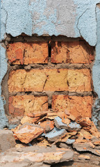 Red stone background. The shabby facade of the building with damage and sprinkled with blue paint.