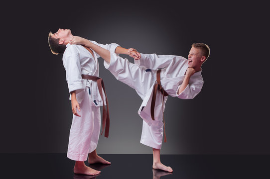 Handsome young male karate player doing kick on the gray background