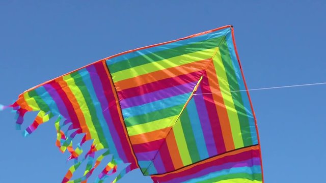 Aquilone con colori dell'arcobaleno che vola in aria con sfondo blu del cielo.