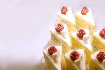 Closeup and crop vanilla cream cake slice with fresh strawberry for sale in cafe.