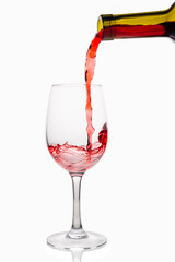 Red wine pouring into wine glass isolated on white background.