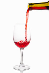 Red wine pouring into wine glass isolated on white background.
