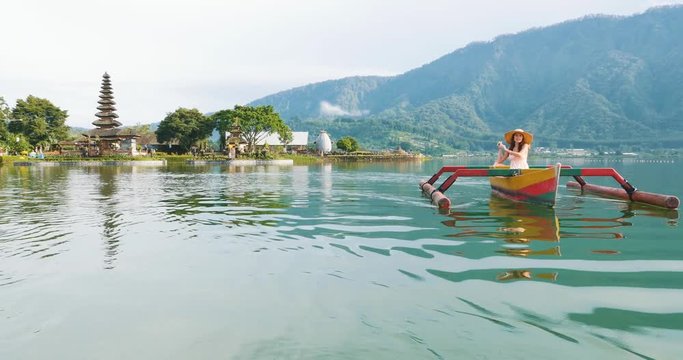 Beautiful girl kayaking on the catamaran at the ulun datu pura bratan temple, in Bali.